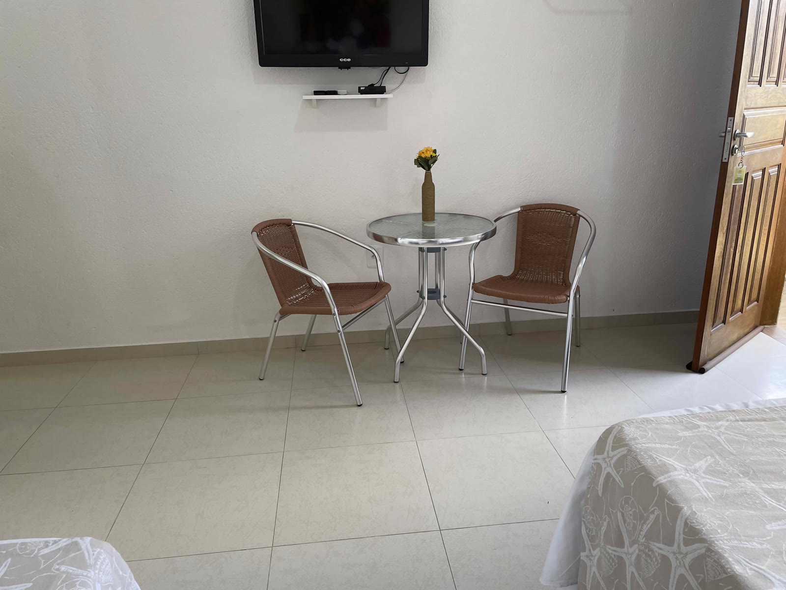 Mesinha redonda com duas cadeiras e um vaso de flores amarelas